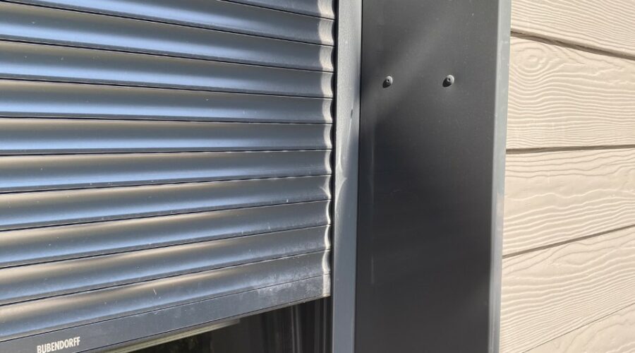 Détail de l'extension moderne en ossature bois avec bardage gris foncé, montrant les finitions des menuiseries et les brise-soleil horizontaux.
