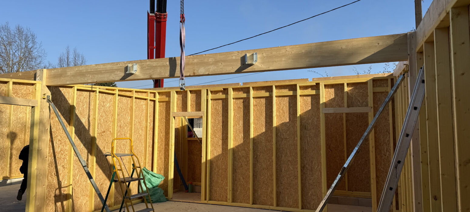 Pose de charpente et poutre porteuse à l'intérieur d'une extension en ossature bois